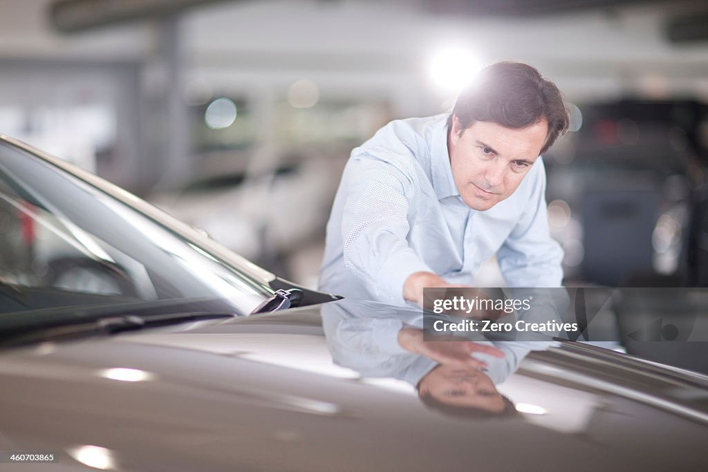 Mid adult man looking at car bonnet in showroom