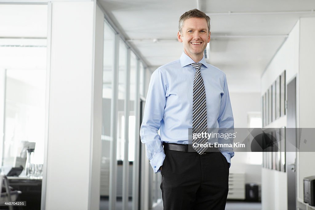 Portrait of mature businessman in office, hands in pockets