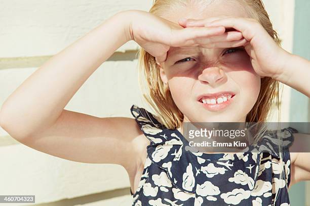 child covering her eyes from sun glare - entrecerrar los ojos fotografías e imágenes de stock