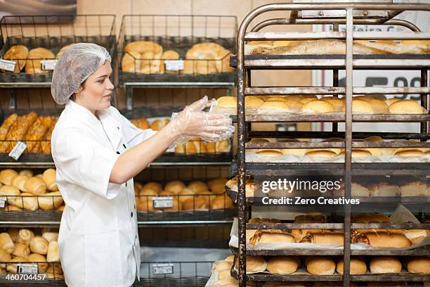 young sales assistant with trays of bread - supermarket bread stock-fotos und bilder