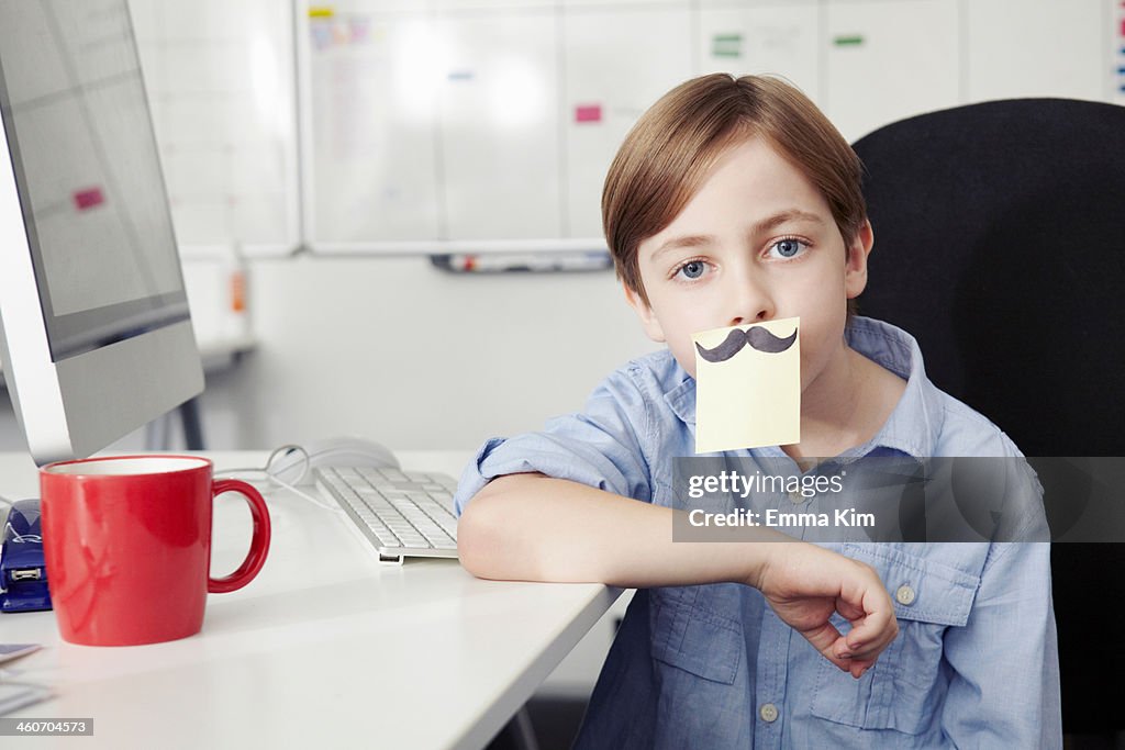 Boy with adhesive note covering mouth, drawing of moustache