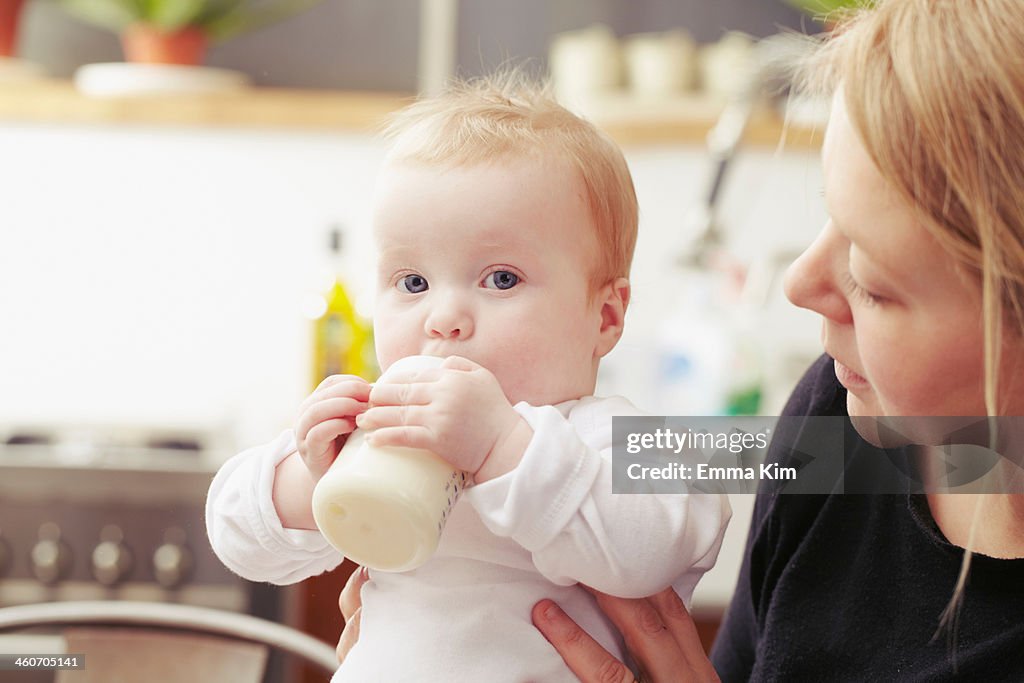 Mother and baby sitting in kitchen with baby bottle