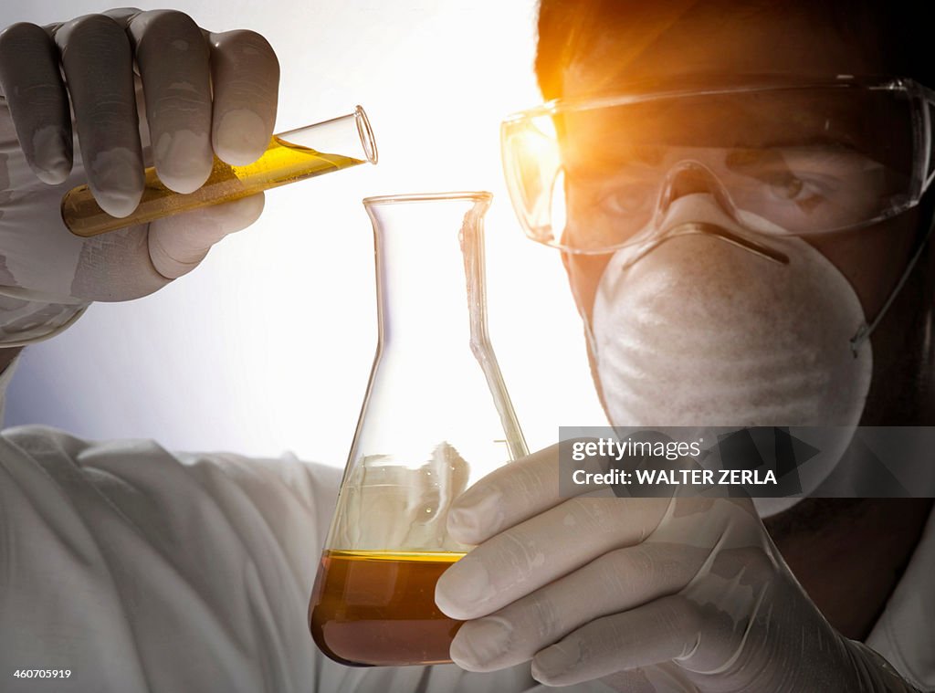 Close up of scientist pouring liquid into flask