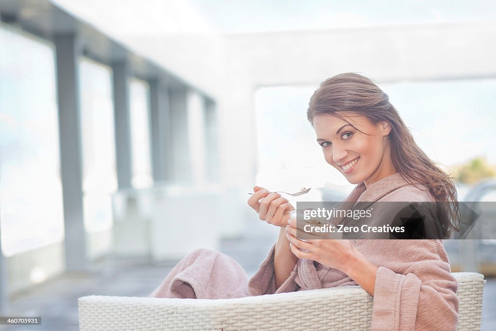 Woman at hotel poolside eating yogurt