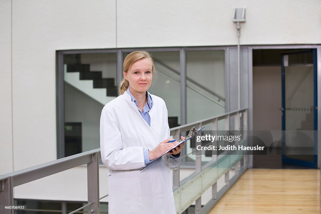Female scientist in atrium with clipboard