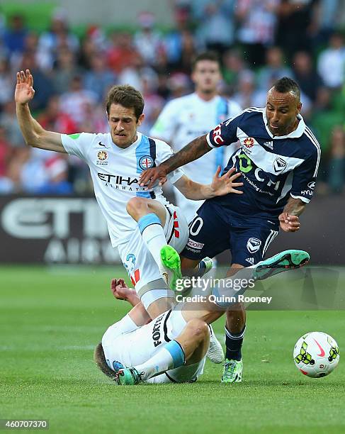 Archie Thompson of the Victory is tackled by Mate Dugandzic and Jacob Melling of City during the round 12 A-League match between Melbourne City FC...