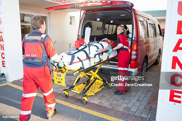 paramedics lifting patient from ambulance - adrenaline stress stock pictures, royalty-free photos & images