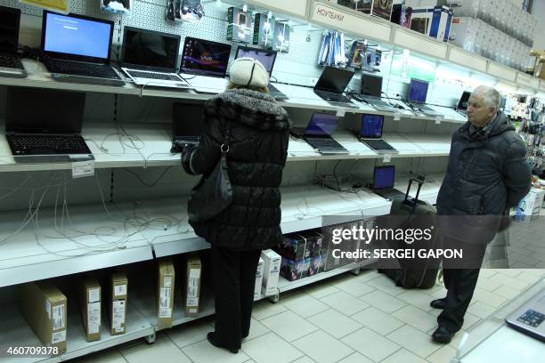 Customers look at laptops in a shop in Klintsy, Bryansk region, some 560 km southwest of Moscow, on December 20, 2014. Belarusians have started to go...