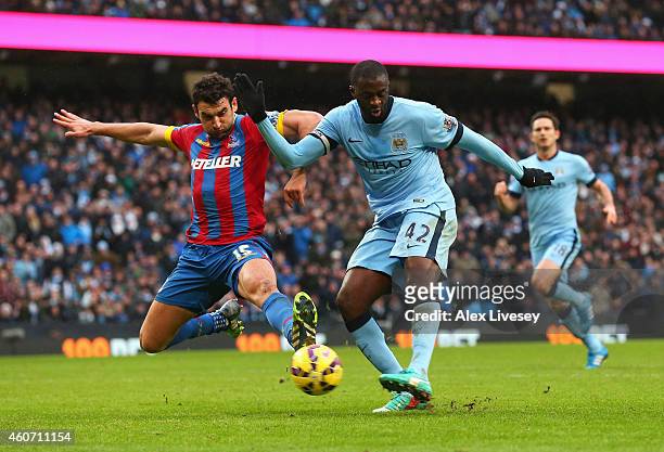 Yaya Toure of Manchester City scores his goal challenged by Mile Jedinak of Crystal Palace during the Barclays Premier League match between...