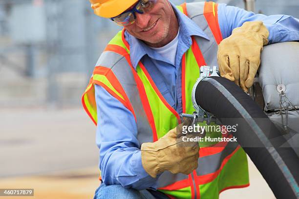 electrical engineer inspecting hose connection for cooling supply lines at power plant - industrial hose stockfoto's en -beelden