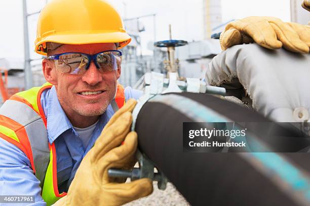 engineer at electric power plant examining hose for water supply to the water storage tank - industrial hose stockfoto's en -beelden