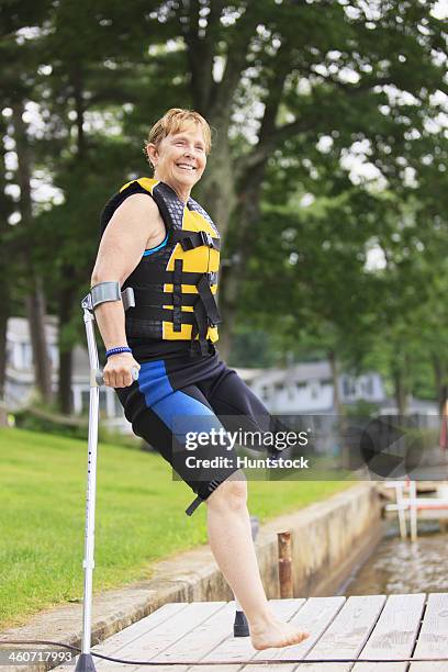 Woman with a prosthetic leg and crutches heading for waterskiing from the dock