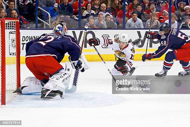 David Savard of the Columbus Blue Jackets knocks down Daniel Carcillo of the Chicago Blackhawks as he attempts to get a shot off on Sergei Bobrovsky...