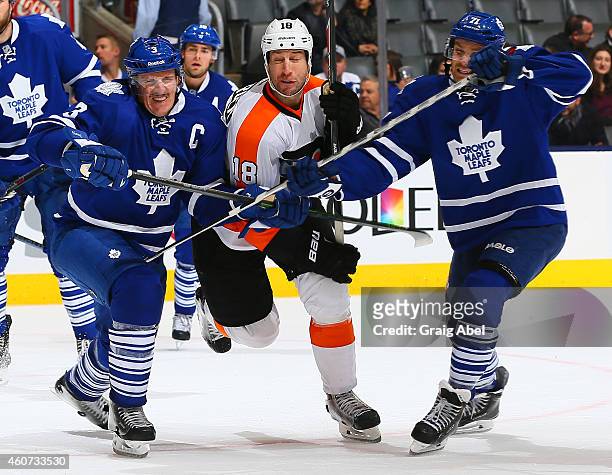 Dion Phaneuf and David Clarkson of the Toronto Maple Leafs hold up R.J. Umberger of the Philadelphia Flyers during NHL game action December 20, 2014...