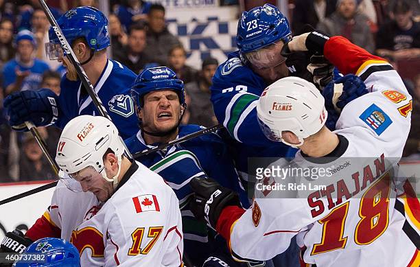 Kevin Bieksa of the Vancouver Canucks reacts after getting hit while in a scrum while Alexander Edler battles with Matt Stajan of the Calgary Flames...