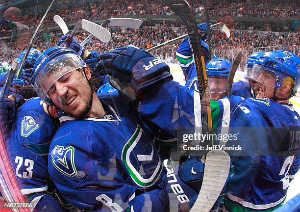 Christopher Tanev of the Vancouver Canucks is mobbed by teammates after scoring in overtime against the Calgary Flames during the NHL game at Rogers...