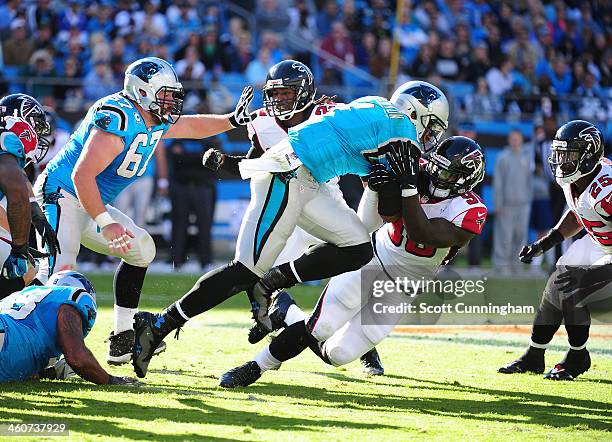 Cam Newton of the Carolina Panthers scrambles against Stansly Maponga of the Atlanta Falcons at Bank of America Stadium on November 3, 2013 in...