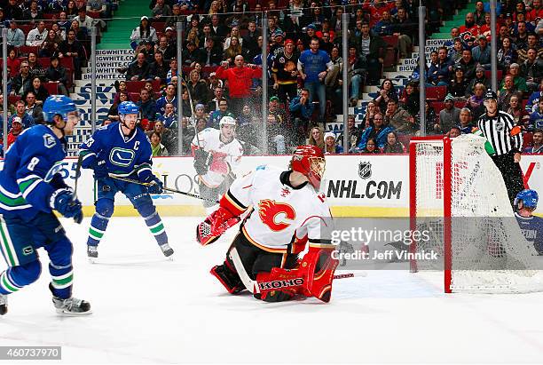 Henrik Sedin of the Vancouver Canucks watches as Christopher Tanev of the Canucks scores in overtime against Jonas Hiller of the Calgary Flames...