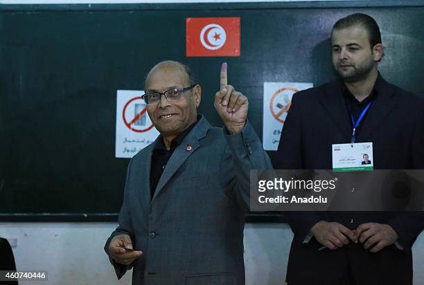 Tunisian presidential candidate Moncef Marzouki demonstrates his painted finger after casting his vote at Sidi el Kantaoui school during the second...