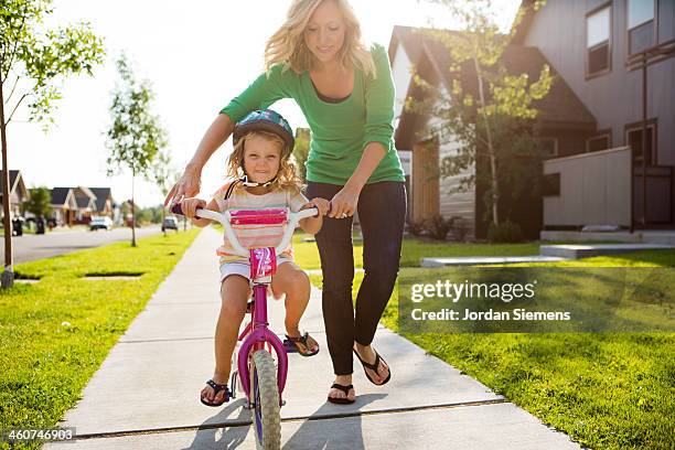 young girl learning to ride a bike. - bicycle daughter stock-fotos und bilder
