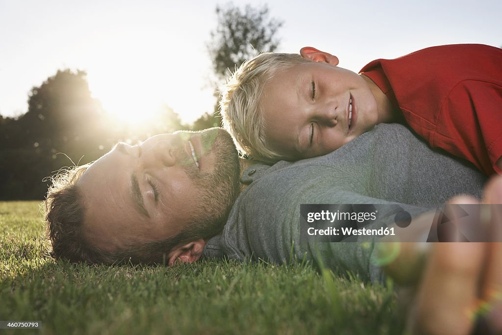 Germany, Cologne, Father and son sleeping in meadow