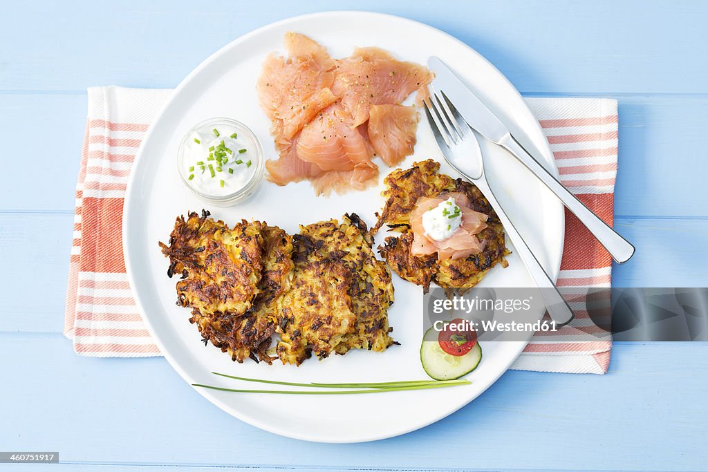Smoked salmon with fried mashed potatoes and spring curd cheese with chives, close up