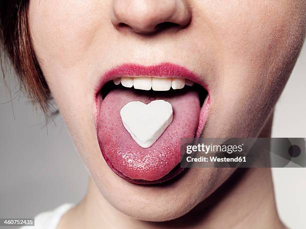 young woman with candy heart on tongue, close up - candy lips stock pictures, royalty-free photos & images