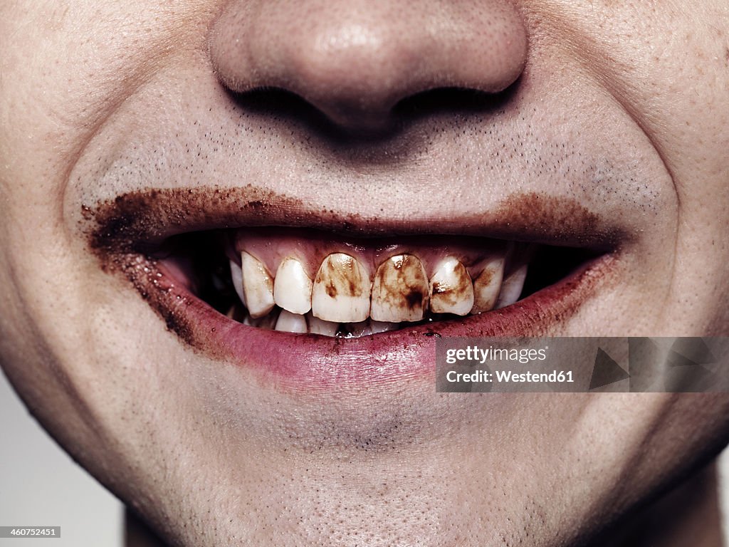 Young man teeth with chocolate, close up