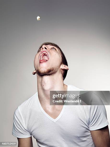 young man playing with popcorns - boca abierta fotografías e imágenes de stock