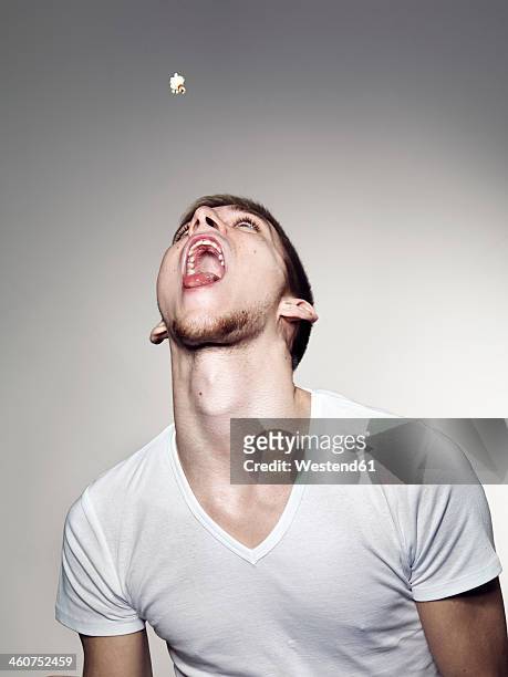 young man playing with popcorns - afferrare foto e immagini stock