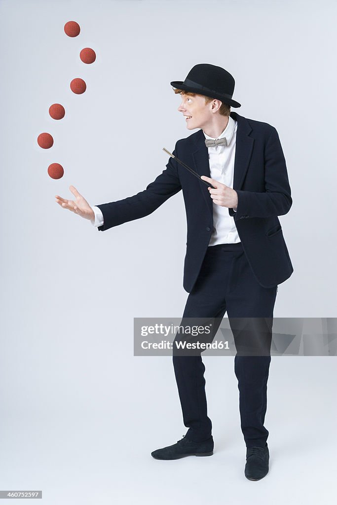 Young man showing magic with ball, smiling