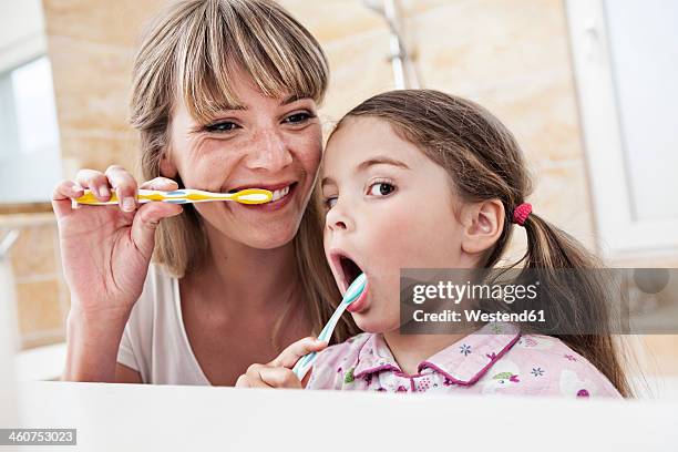 germany, north rhine westphalia, cologne, mother and daughter brushing teeth in bathroom - bad bangs stock-fotos und bilder