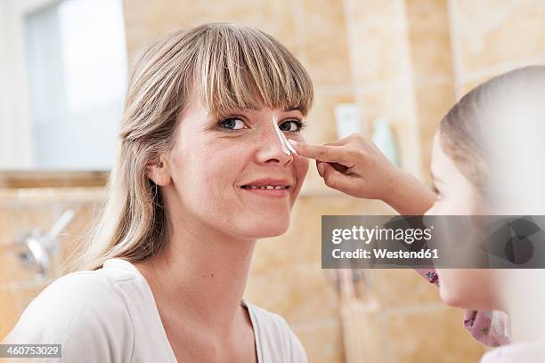 germany, north rhine westphalia, cologne, daughter applying cream to mother in bathroom, smiling - bad bangs stock-fotos und bilder