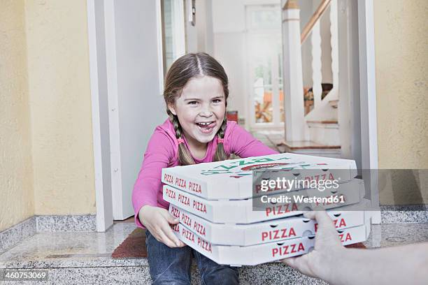 germany, north rhine westphalia, cologne, girl taking pizza boxes from delivery man, smiling - pizza delivery stock-fotos und bilder