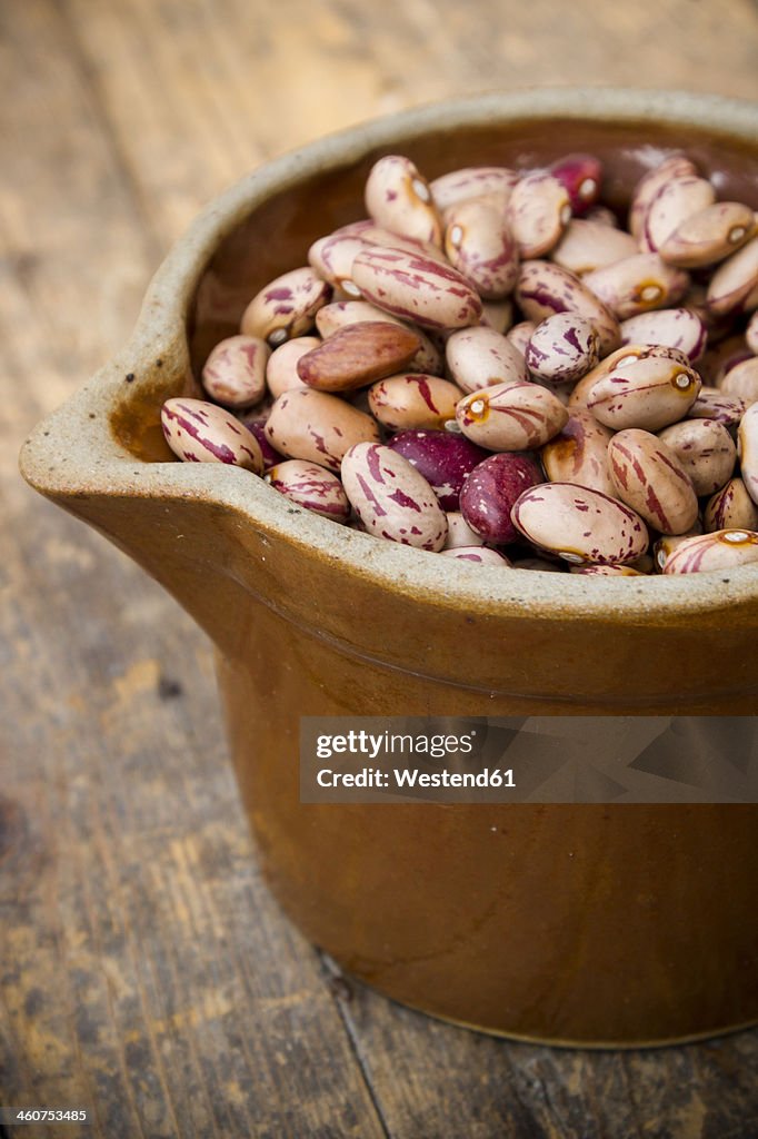 Bowl of borlotti beans on wooden table, close up