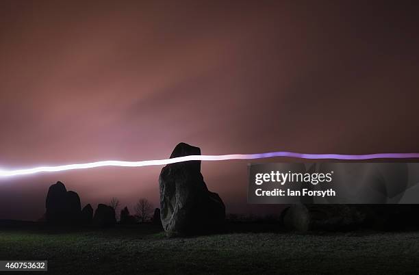 Woman wearing a head torch forms a light trail across the standing stones during the evening of the Winter Solstice at the Castlerigg Stone circle on...
