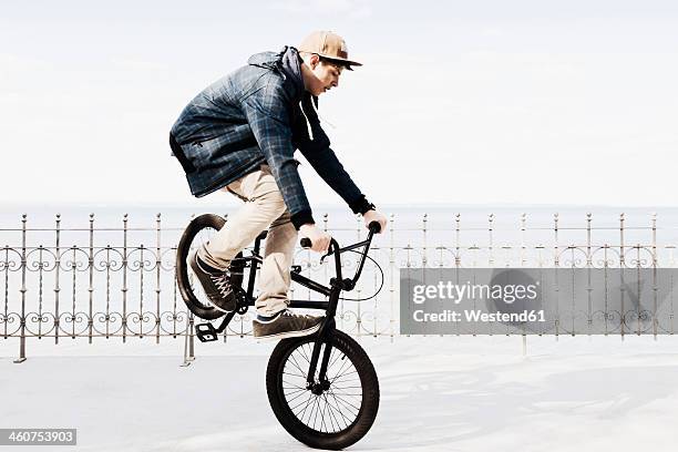 germany, schleswig holstein, teenage boy jumping with bmx bike - crossfietsen stockfoto's en -beelden