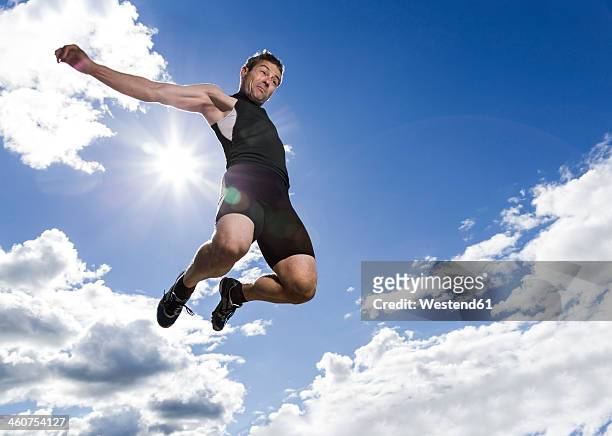 germany, mature man doing long jump - mens long jump stockfoto's en -beelden