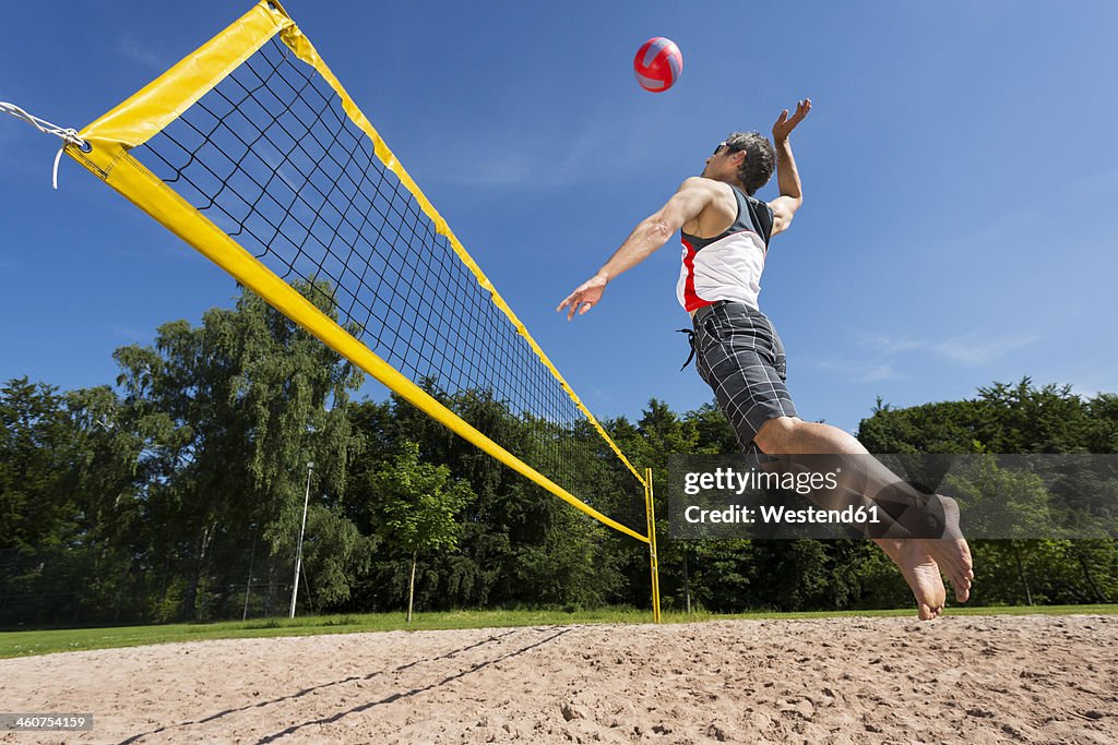 Germany, Mature man playing beach volleyball