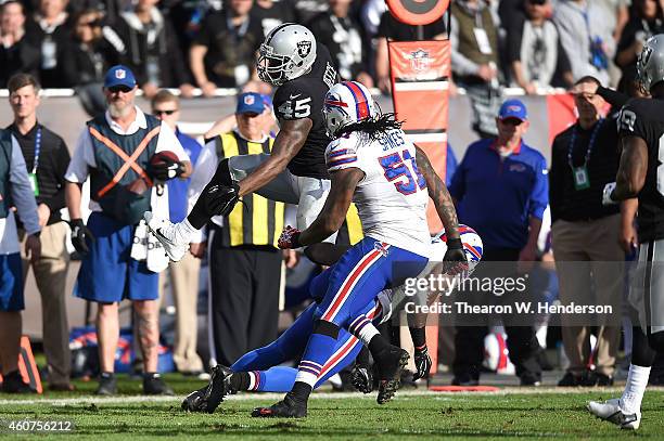 Marcel Reece of the Oakland Raiders leaps over Corey Graham of the Buffalo Bills with pressure from Brandon Spikes of the Buffalo Bills in the second...