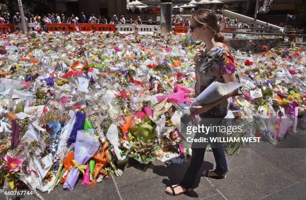 Woman arrives with a bouquet of flowers to add to the floral tributes left in Sydney's Martin place, one week after a siege at the Lindt cafe which...