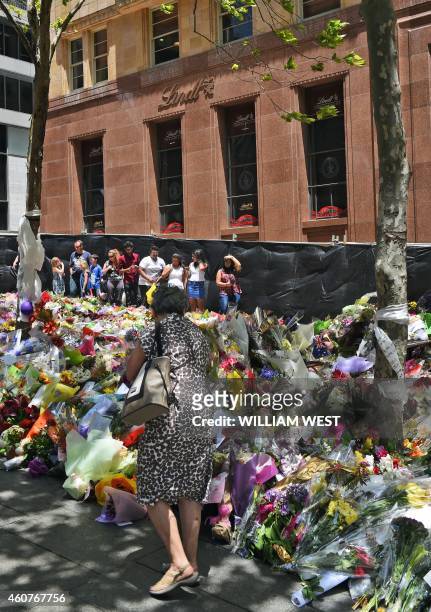People look at the floral tributes left outside the Lindt cafe in Sydney's Martin Place, one week after a siege at the cafe which saw two hostages...