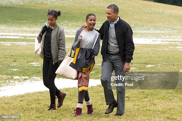 President Barack Obama and his daughters Malia and Sasha walk across the South Lawn of the White House after arriving by Marine One January 5, 2014...