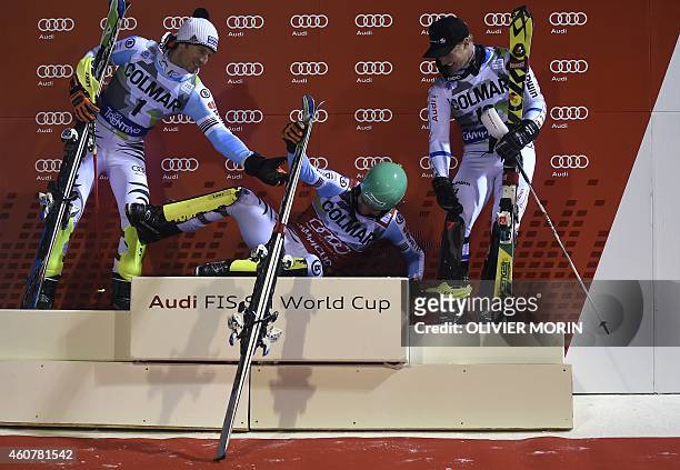 Second placed Germany's Fritz Dopfer and third placed Sweden's Jens Byggmark assists first placed Germany's Felix Neureuther onto the podium after...