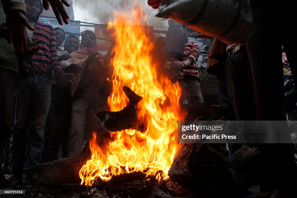 People warm themselves around a bonfire on a foggy and cold...