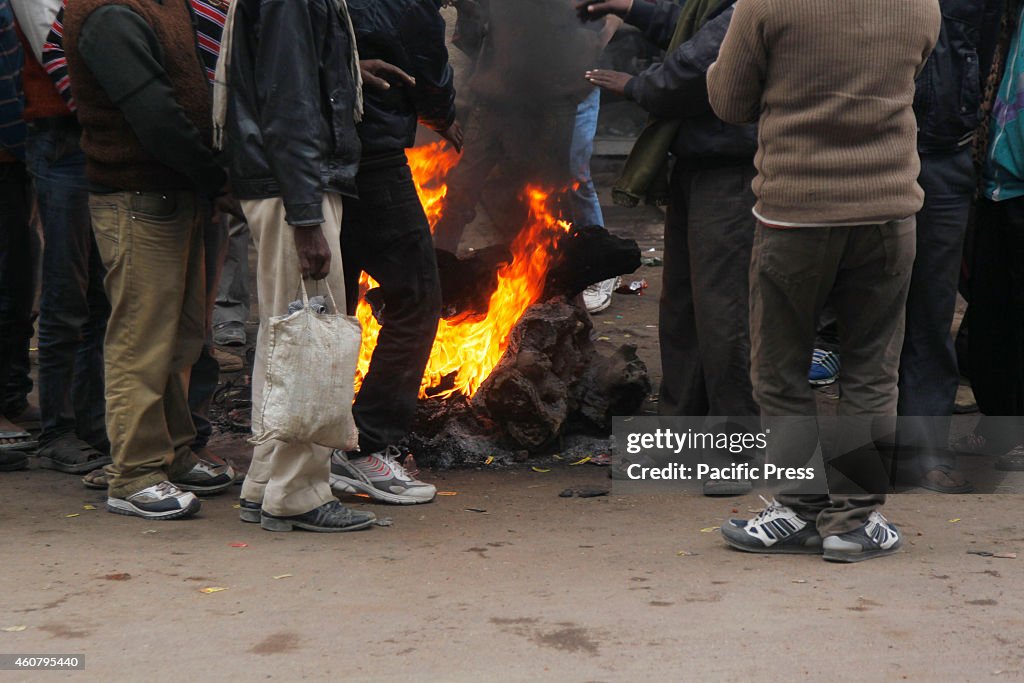 People warm themselves around a bonfire on a foggy and cold...