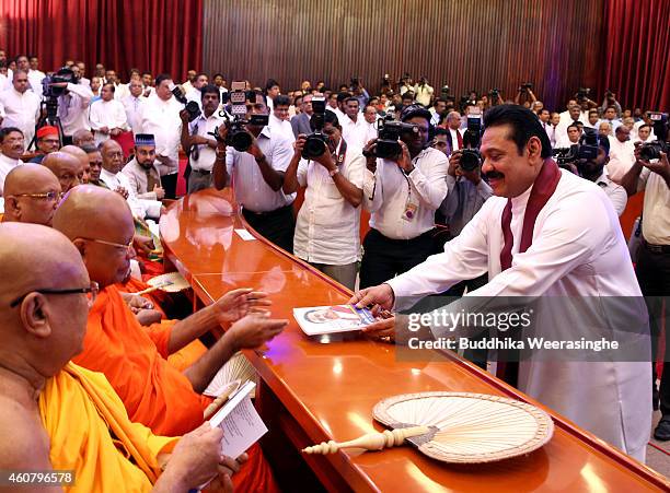 Sri Lankan President Mahinda Rajapaksa gives his party manifesto for Buddhist monks during the meeting to announce the party election manifesto on...