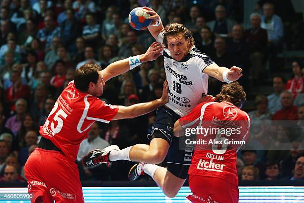 Lars Kaufmann of Flensburg-Handewitt is challenged by Michael Mueller and Johannes Sellin of Melsungen during the DKB Handball Bundesliga match...