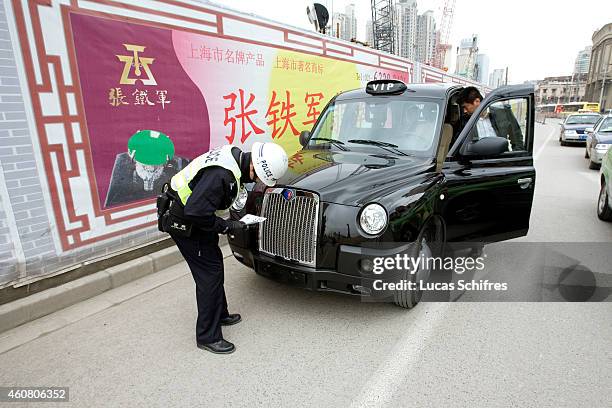Chinese motorcycle policeman checks a 'black cab' on March 23, 2009 in Shanghai, China. London Taxi International, the producer of London Taxi's...