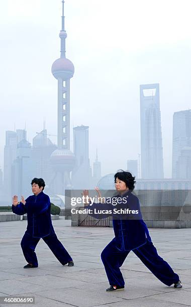 Two women practice the Chinese martial art tai-chi at dawn on the Bund on February 1, 2009 in front of the Oriental Pearl tower and the World...